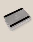 The Analog Capture Kit - Small (Silver Aluminum), a rectangular tray with rounded edges and black grooves, displays the white UGMONK logo on its lid and rests on a light beige surface—ideal for organizing your Small Dot Grid Cards.