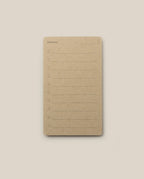 A brown notepad inspired by the Analog - Someday Cards, featuring “Someday” printed at the top. Each page offers ten numbered lines for writing and a blank space for the date in the upper right corner—perfect for creative goal setting. The notepad is centered on a light beige background.