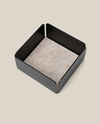 The Warehouse Item - Gather Small Tray (1x1 - Black) is a square black metal organizer with a light gray felt bottom, displayed on a neutral beige background. Ideal for keeping essentials tidy, this small tray is an excellent pick from the warehouse sale selection.