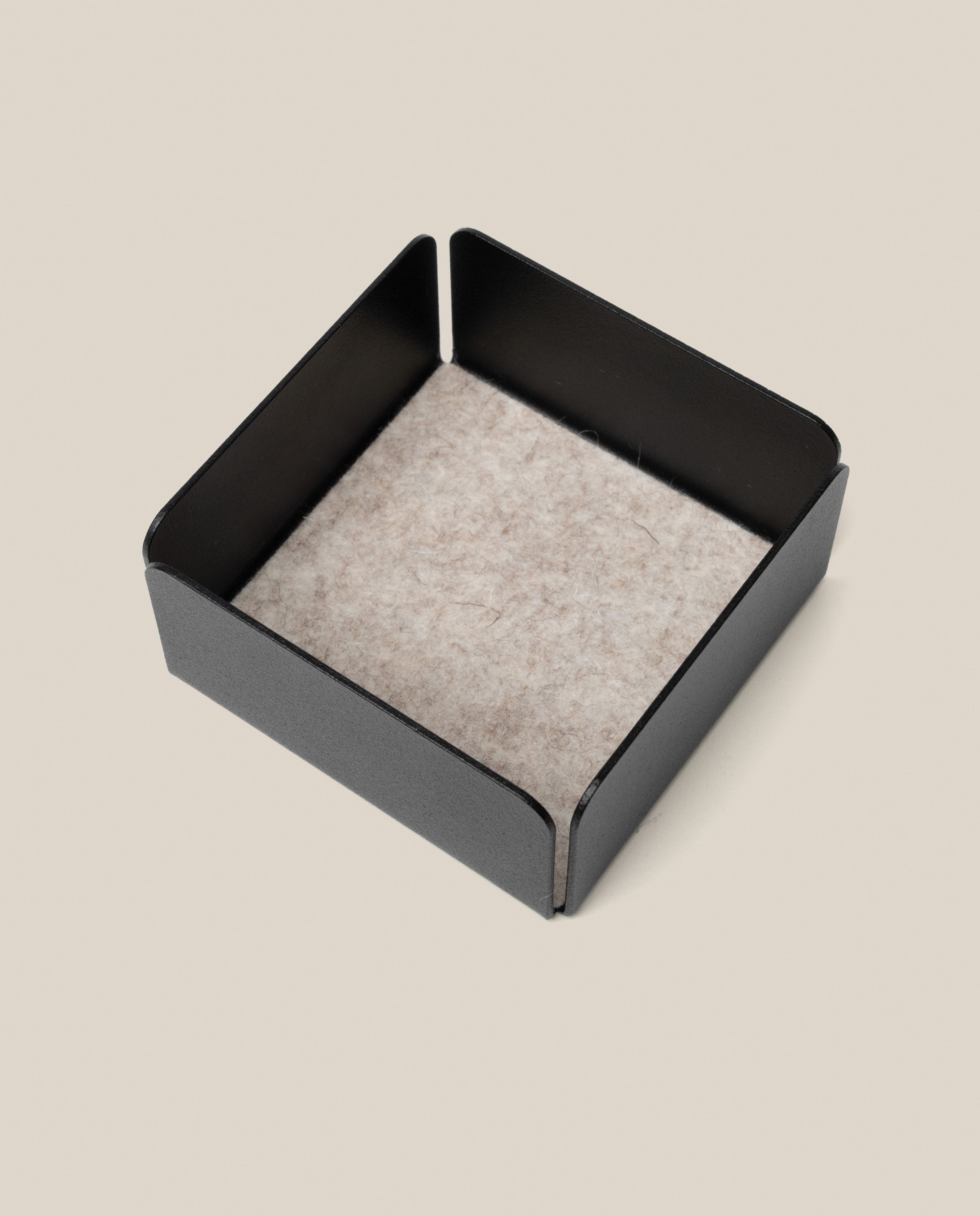 The Warehouse Item - Gather Small Tray (1x1 - Black) is a square black metal organizer with a light gray felt bottom, displayed on a neutral beige background. Ideal for keeping essentials tidy, this small tray is an excellent pick from the warehouse sale selection.