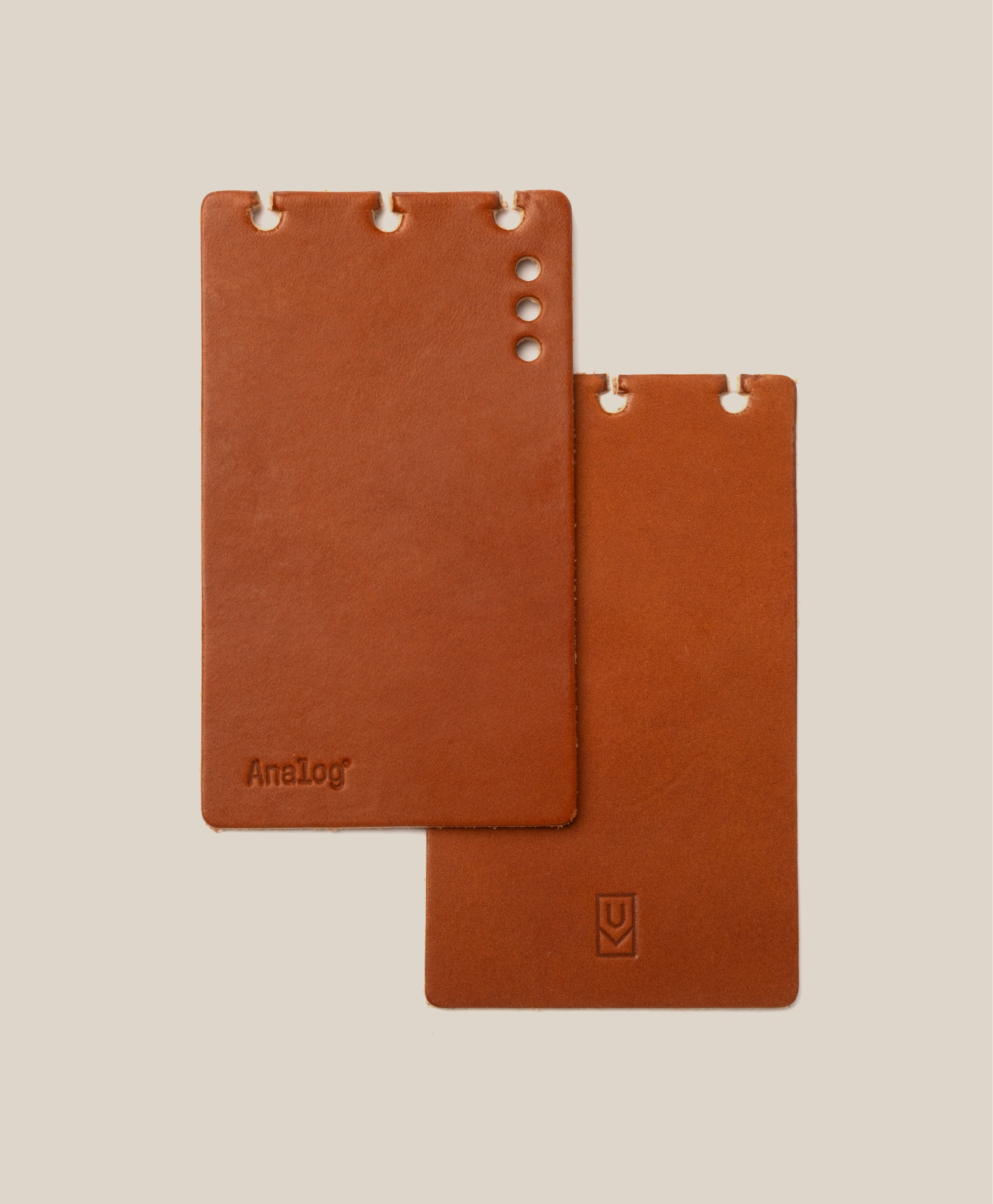 Two tan full-grain leather *Covers Only* – Leather Discbound Analog rest on a beige background. Designed for Discbound Analog systems and made in the USA, one cover features four circular holes and an "AnaLog" stamp, while the other displays three notches with a small logo near its bottom edge.