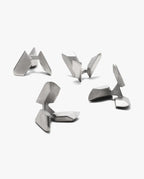 Four Craighill Tetra Puzzles, crafted from stainless steel, are arranged on a plain white background. Each puzzle features sharp edges and geometric forms, embodying a modern and minimalistic aesthetic.