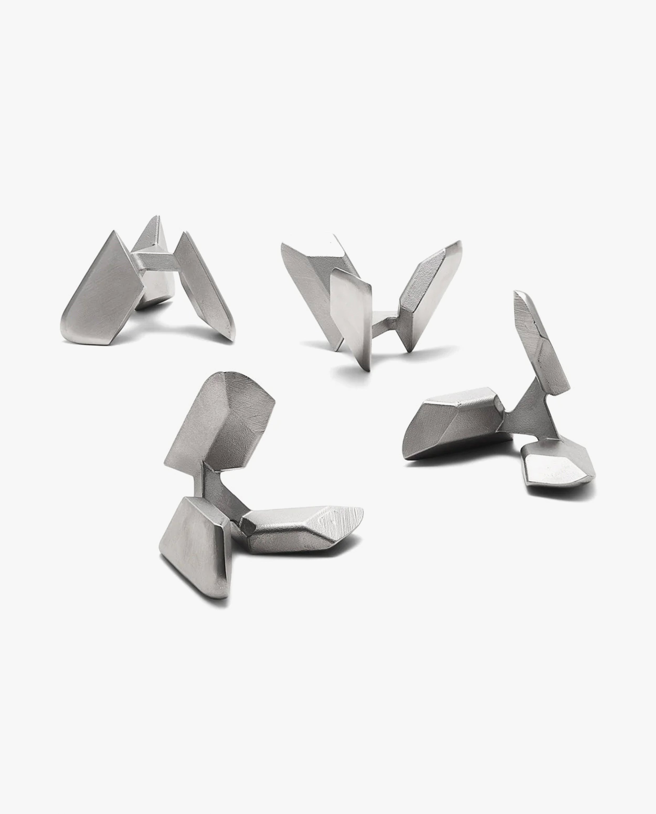 Four Craighill Tetra Puzzles, crafted from stainless steel, are arranged on a plain white background. Each puzzle features sharp edges and geometric forms, embodying a modern and minimalistic aesthetic.