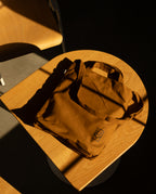 Ugmonk Utility Tote (Field Tan) heavyweight cotton utility tote bag with a small square logo, sitting on a wooden stool.