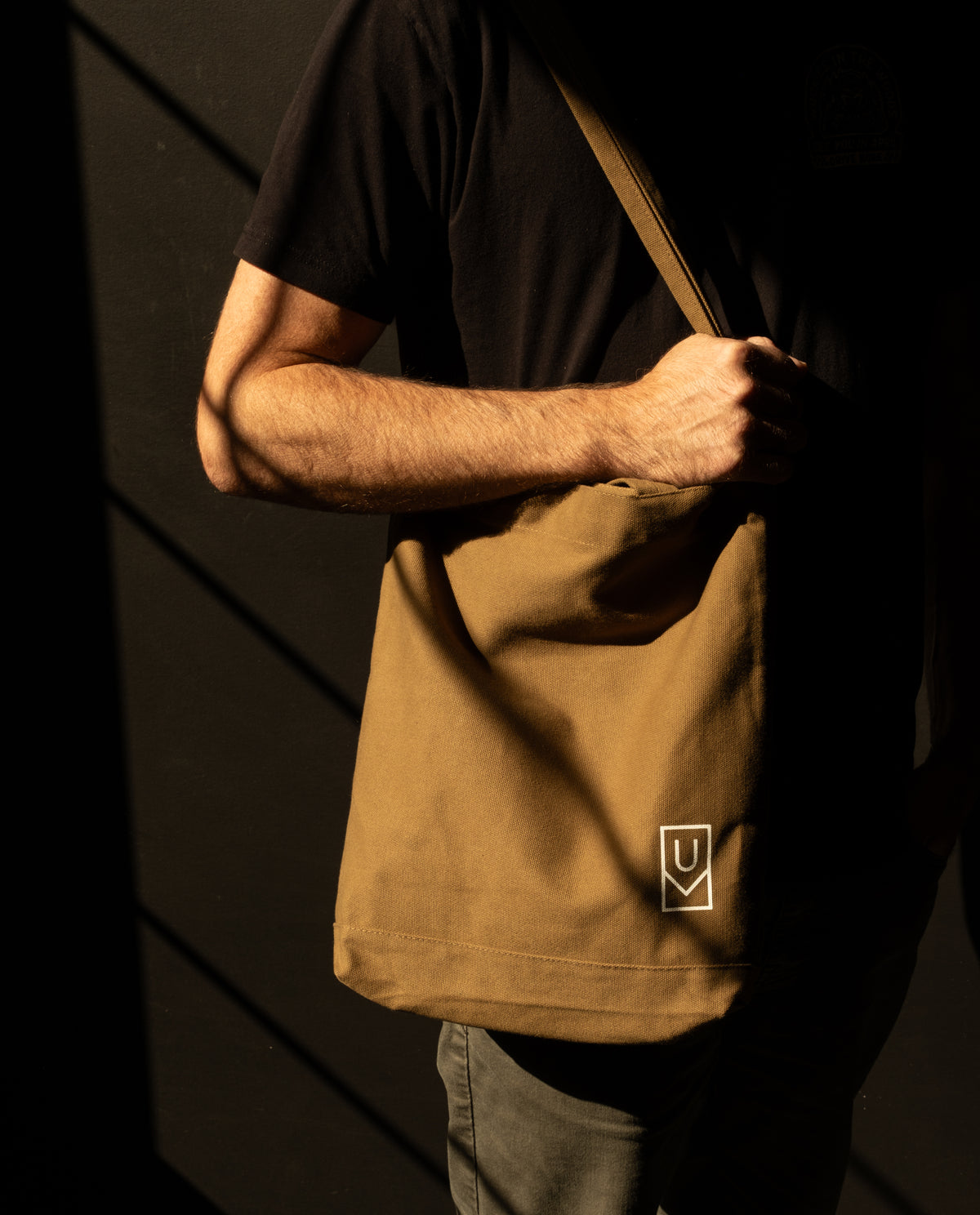 A person carries an olive Ugmonk Utility Tote (Olive) heavyweight cotton bag with a small white logo on the lower corner.