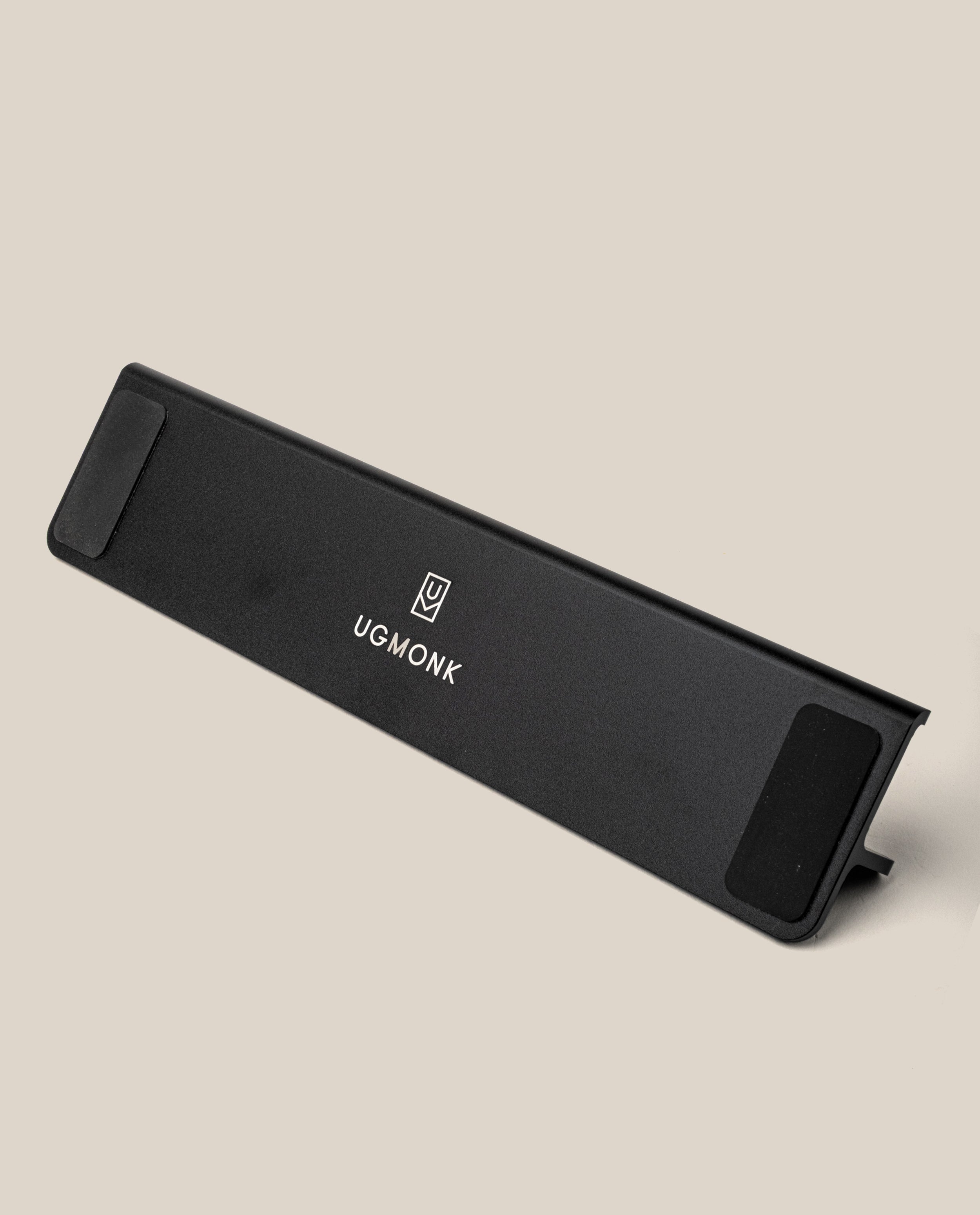 A black, rectangular wrist rest featuring the Ugmonk logo and name in white, displayed on a neutral beige background—perfect to pair with your Analog Annual Kit (Black Aluminum).
