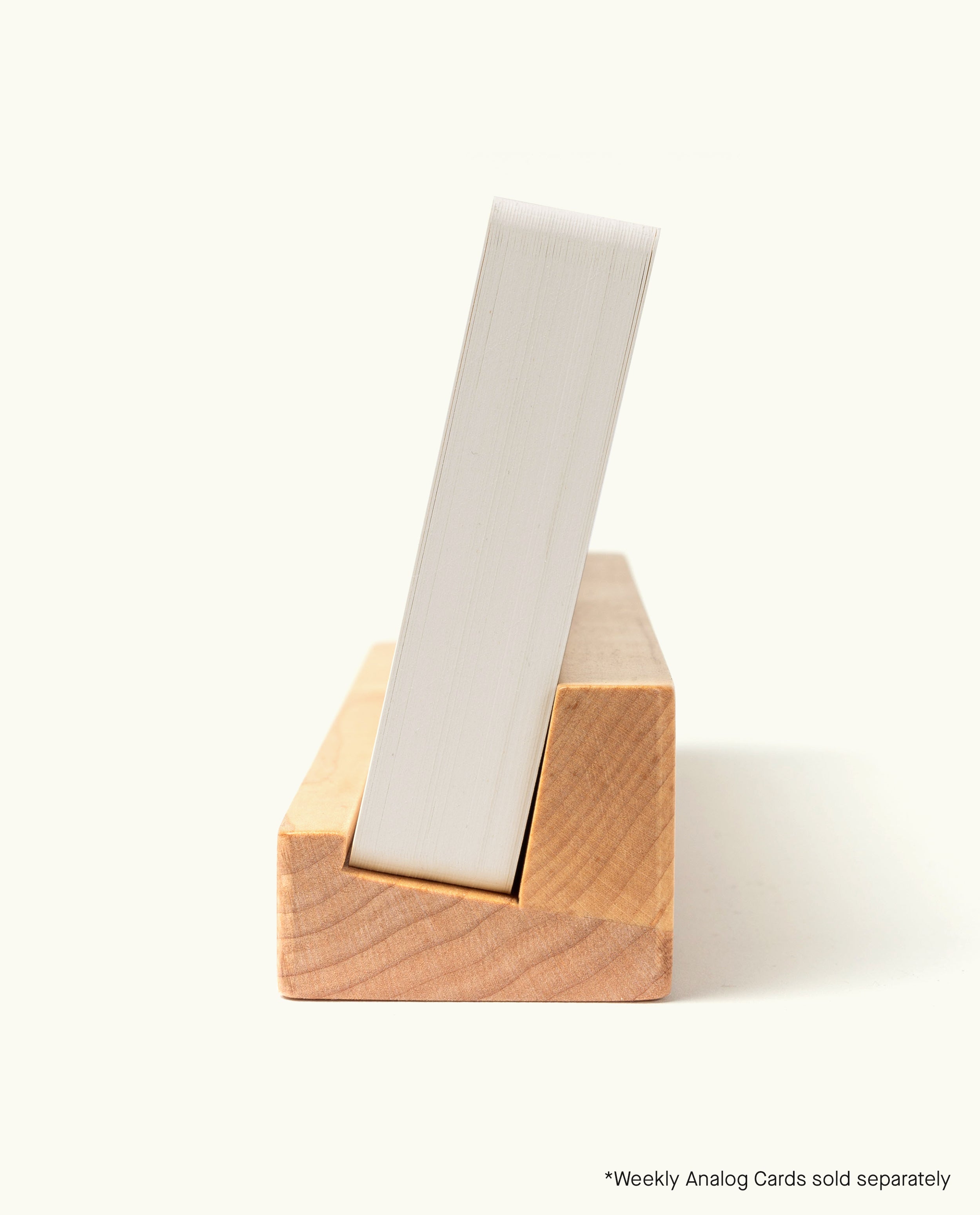 A handcrafted in Pennsylvania maple card holder, the Analog Weekly Card Holder (Maple), with a stack of white cards inserted vertically, viewed from the side on a light background. Text in the lower right corner reads, “*Analog Weekly Cards sold separately.”.