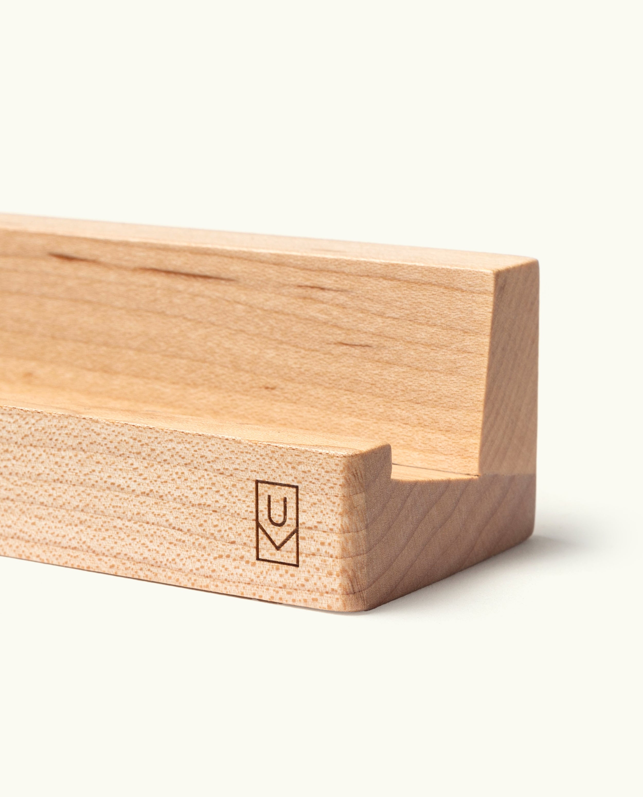 The Analog Weekly Card Holder (Maple) is a handcrafted wooden stand with a simple, minimalist design, featuring a precisely carved groove and a small, engraved geometric logo on the front corner. Made in Pennsylvania, this elegant piece enhances your desk and pairs perfectly with your favorite Analog Weekly Cards for an added touch of organized sophistication.