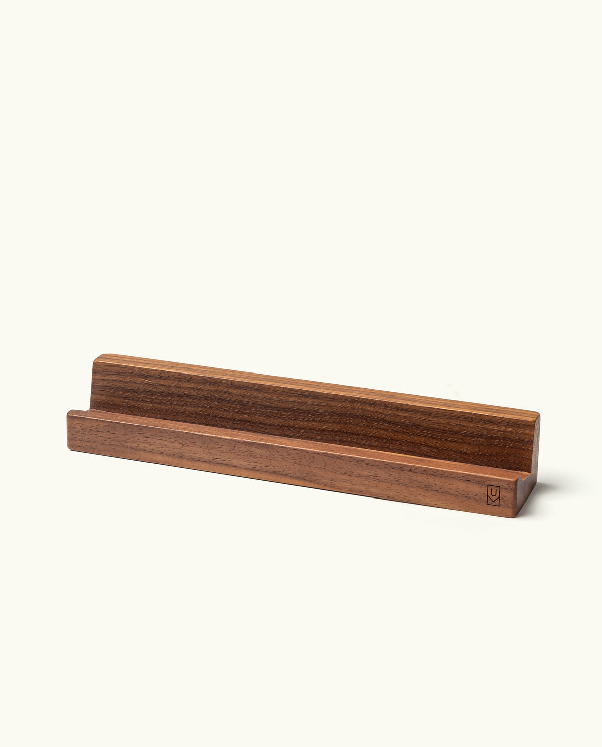 The Analog Weekly Card Holder (Walnut) is handcrafted in Pennsylvania with a groove for displaying Analog Weekly Cards, a tablet, phone, or book—all on a plain light background.