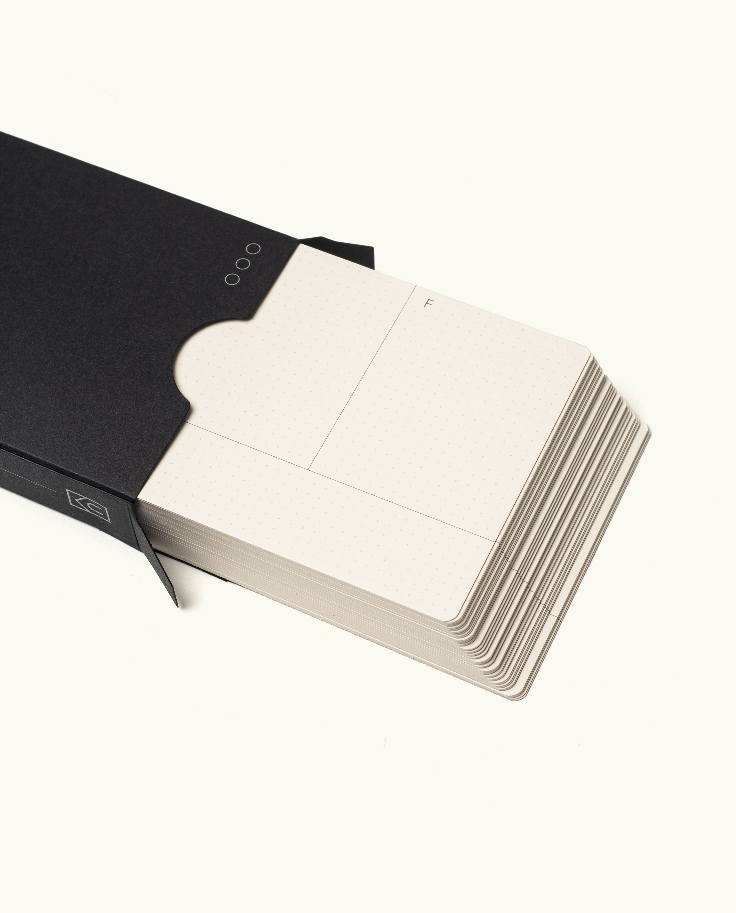 A stack of cream-colored Analog Weekly Cards, partially pulled from a sleek black paper holder. The top card features a divided section and an “F” in the corner—perfect for analog weekly planning setups.