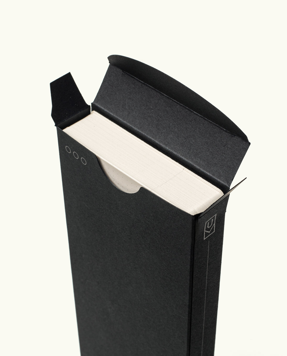 A minimal black cardboard box with a circular cutout partially reveals the edges of Analog Weekly Cards, featuring simple line accents for easy access and a clean design.