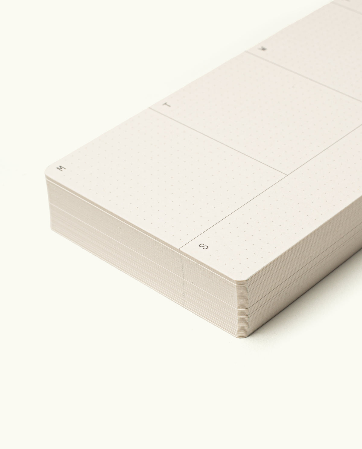A close-up of the corner of Analog Weekly Cards, a minimalistic planner with a sleek analog weekly kit, dot grid layout, and abbreviated weekday labels set against a clean white background.