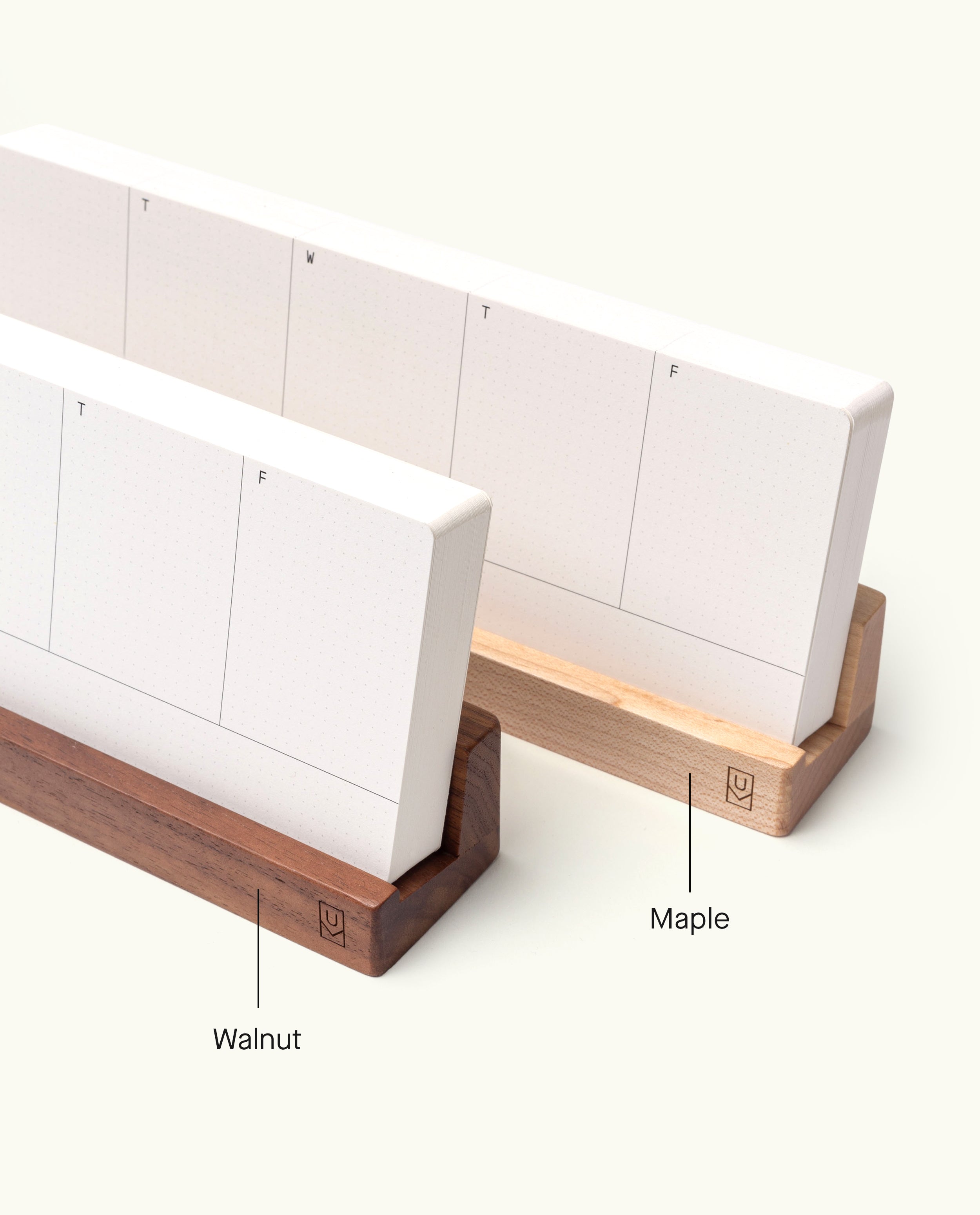 Two Analog Weekly Planning Kits (Walnut) are showcased in refined wooden stands—one in rich dark walnut and the other in light maple, each distinctly labeled. The weekly planner cards display columns for each day of the week and boast a minimalist, modern design, enhanced by the sleek walnut card holder.