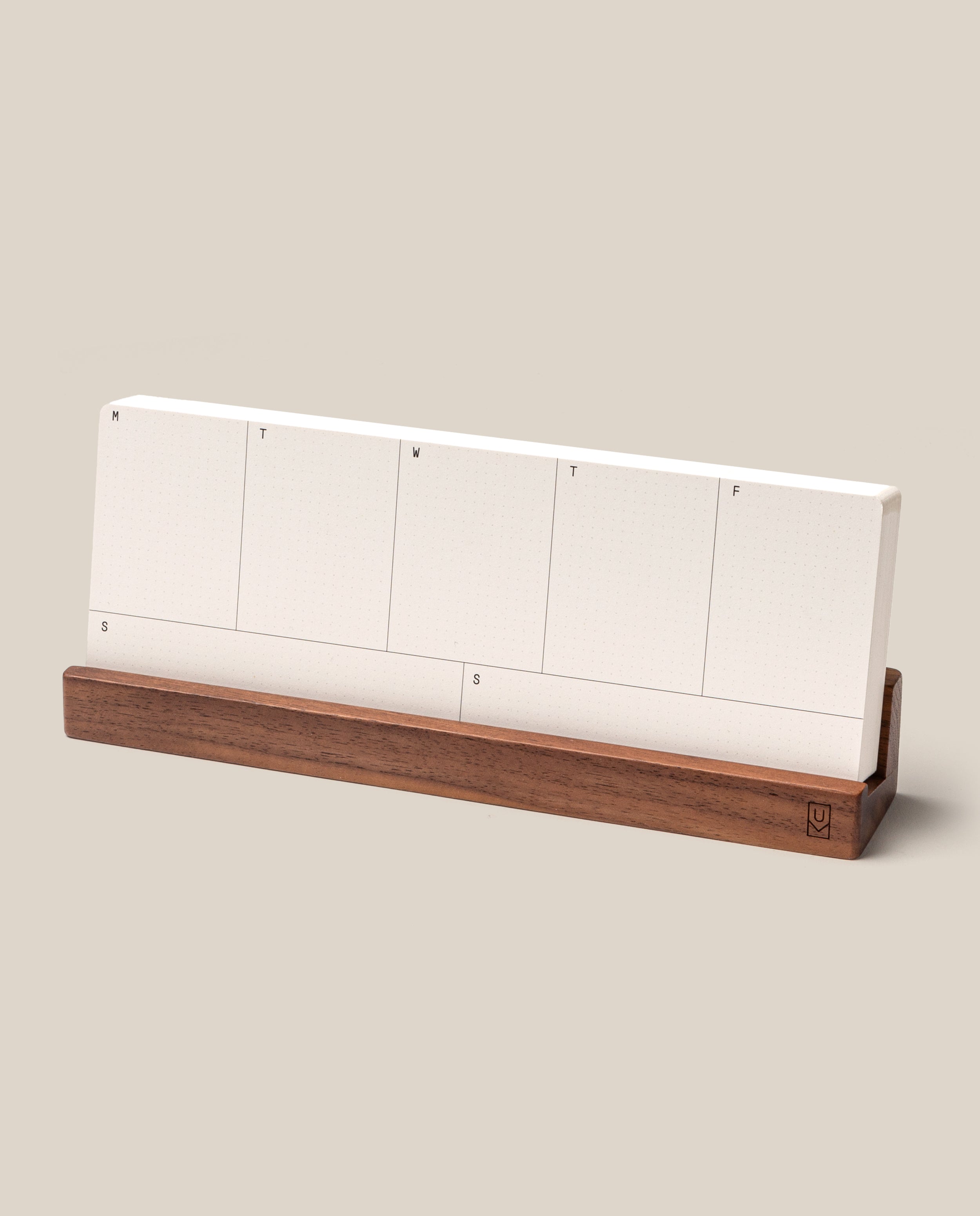 The Analog Weekly Planning Kit (Walnut) features a minimal desk weekly planner with blank white sections for each day, organized on stylish planner cards labeled with the days of the week by their initials. Set in a sleek walnut card holder and complemented by a light beige background, this kit brings both function and elegance to your workspace.