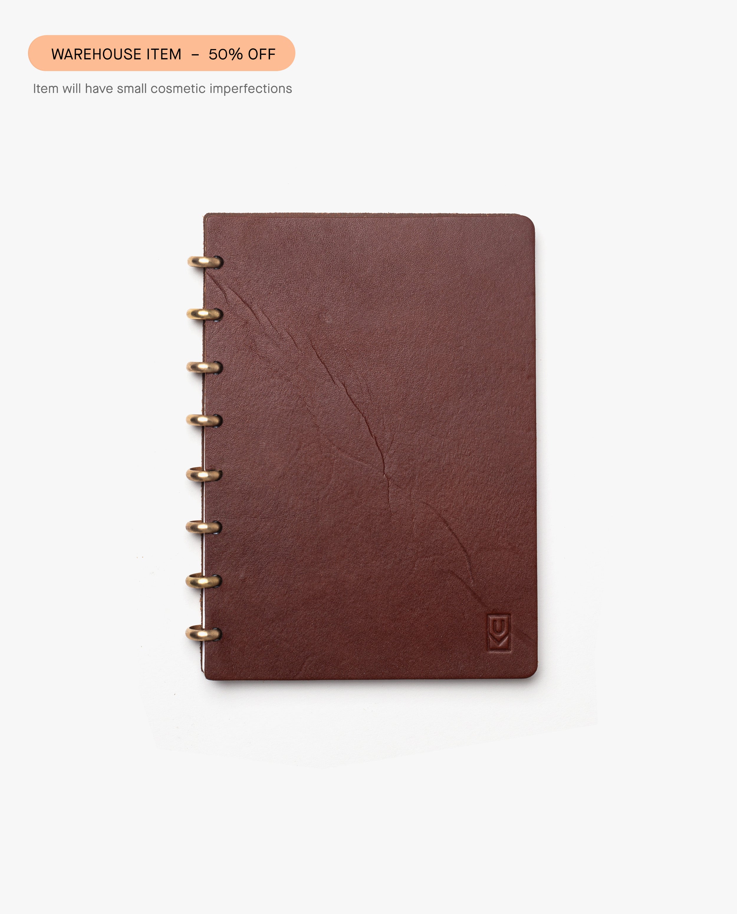 The Warehouse Item - Discbound Heirloom Journal (Brown/Brass), made of full grain leather, is shown with visible creases on the cover. A label reads WAREHOUSE SALE – 50% OFF due to small cosmetic imperfections.