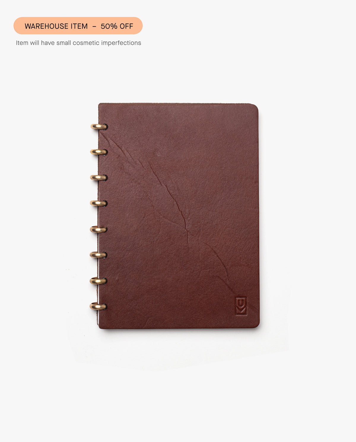 The Warehouse Item - Discbound Heirloom Journal (Brown/Brass), made of full grain leather, is shown with visible creases on the cover. A label reads WAREHOUSE SALE – 50% OFF due to small cosmetic imperfections.