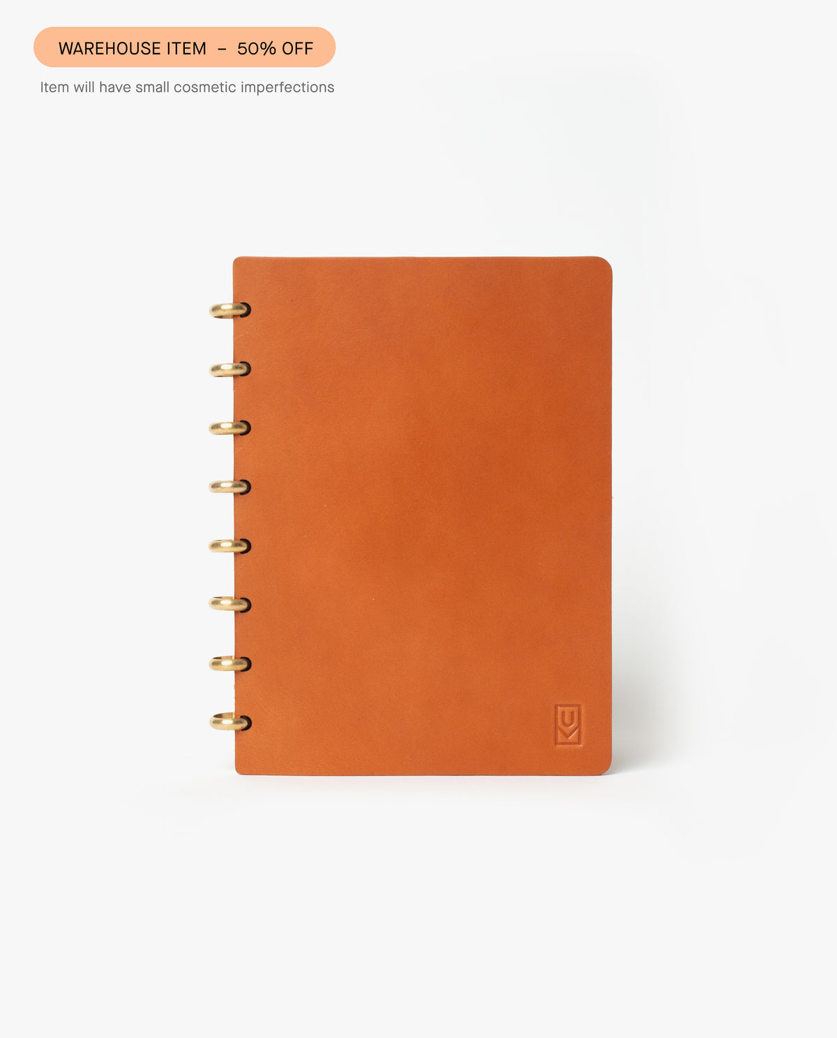 A tan discbound Heirloom Journal with a plain cover and brass discs is centered on a white background. A label above reads, "Warehouse Item - 50% off." This refillable journal may have minor cosmetic imperfections.