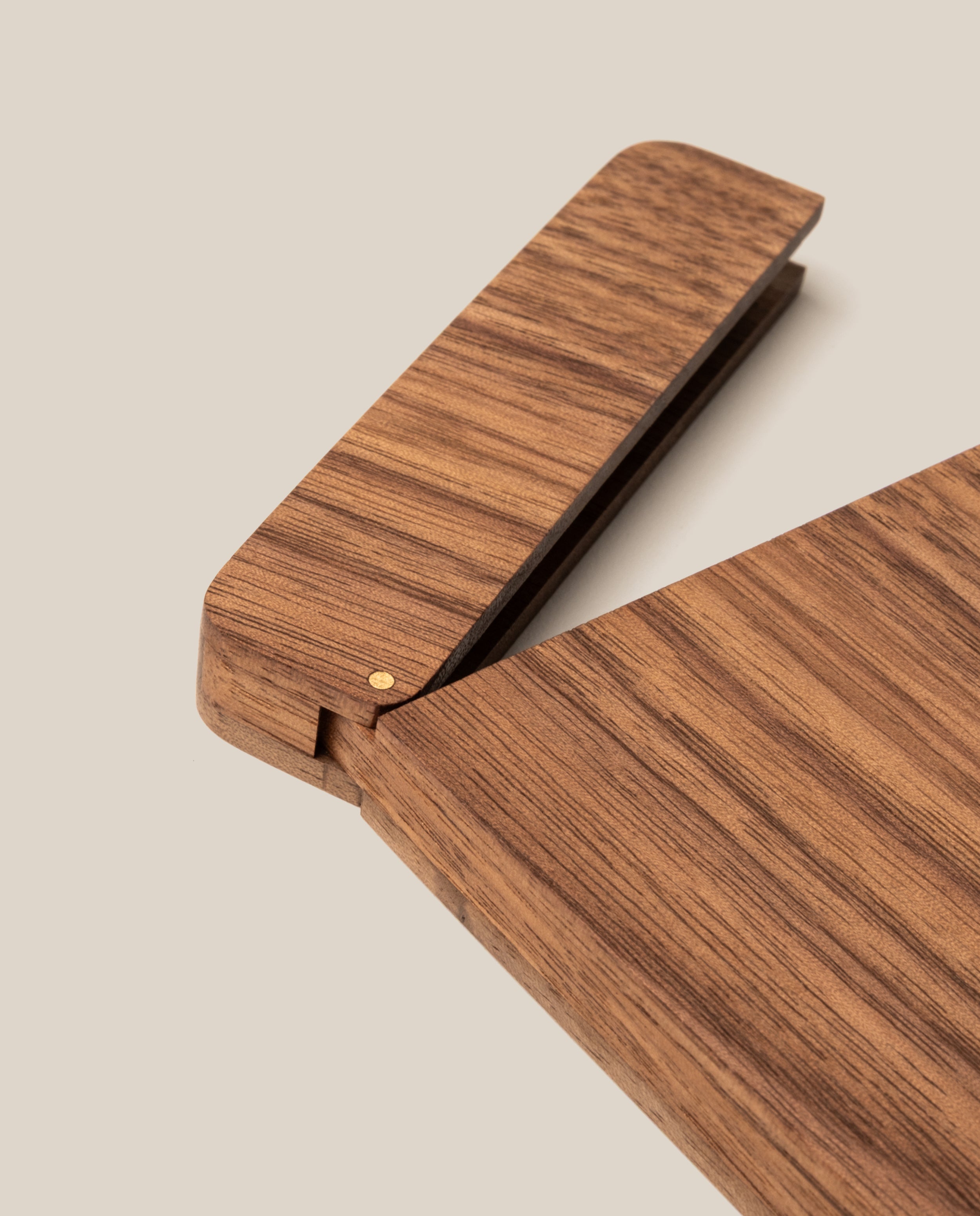 A close-up of The Analog Bundle (Walnut)—a modern, minimalist wooden stapler with a smooth finish—partially open beside a refillable pen on a light beige background.