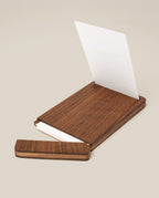 The Analog Bundle (Walnut) features a wooden kit with a sliding lid, shown partially open to display white index cards inside. A single card stands upright in the walnut holder against a plain light beige background.