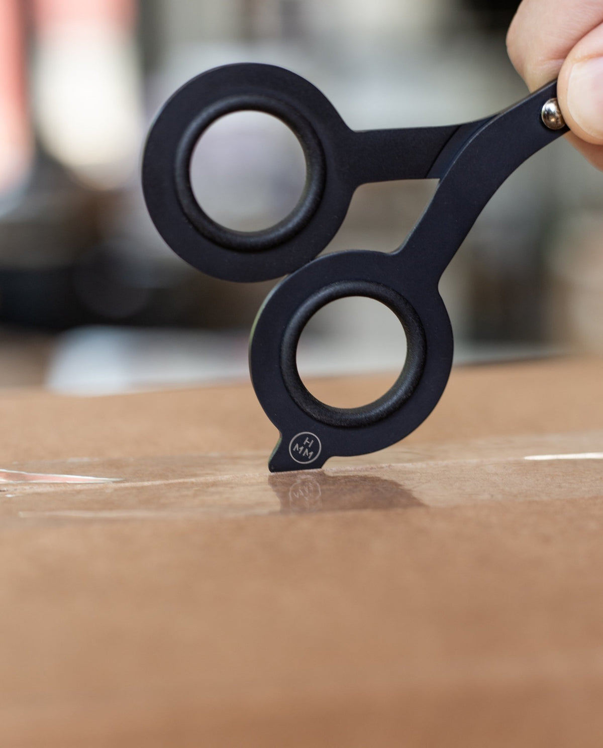 The HMM Scissors (Black), featuring a built-in box cutter, cut a piece of paper.