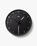 The Braun Wall Clock (Black) features white hour and minute hands, a slim yellow second hand, and silent operation. Clear white tick marks and numbers on a plain white background make the clock easy to read, displaying 10:30:50.