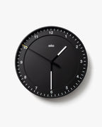 The Braun Wall Clock (Black) features white hour and minute hands, a slim yellow second hand, and silent operation. Clear white tick marks and numbers on a plain white background make the clock easy to read, displaying 10:30:50.