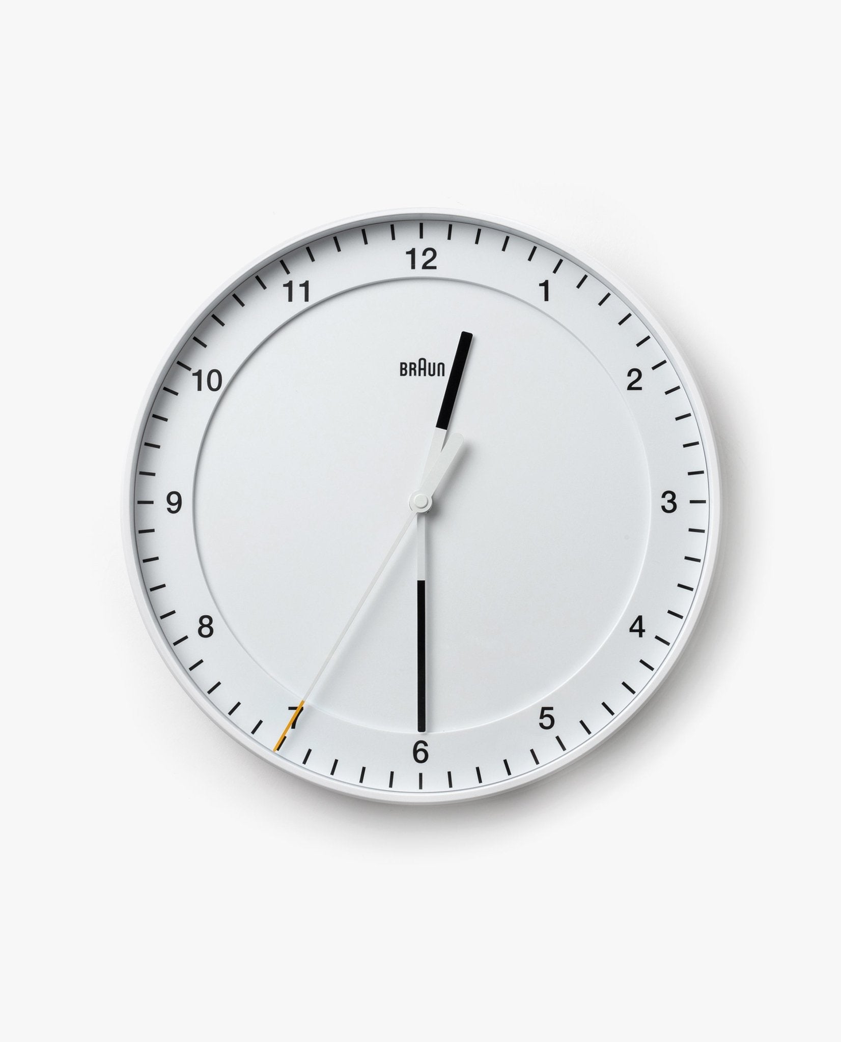 The Braun Wall Clock (White) is a round analog wall clock displaying the time as 12:30:35. The word "Braun" appears below the 12. It features an easy-to-read dial with black hour and minute hands, as well as a thin white silent sweeping second hand tipped in yellow.