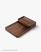 The Small Walnut Valet Tray, handcrafted in Pennsylvania, features rounded edges for elegant everyday carry storage, shown stacked partially atop a larger tray on a white background.