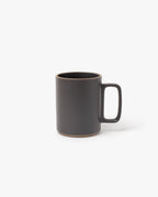 The Hasami Porcelain Mug (Matte Black) features a large rectangular handle and natural brown ceramic edges on the rim and base, highlighting its handmade look inspired by classic Japanese design. Photographed against a plain white background.