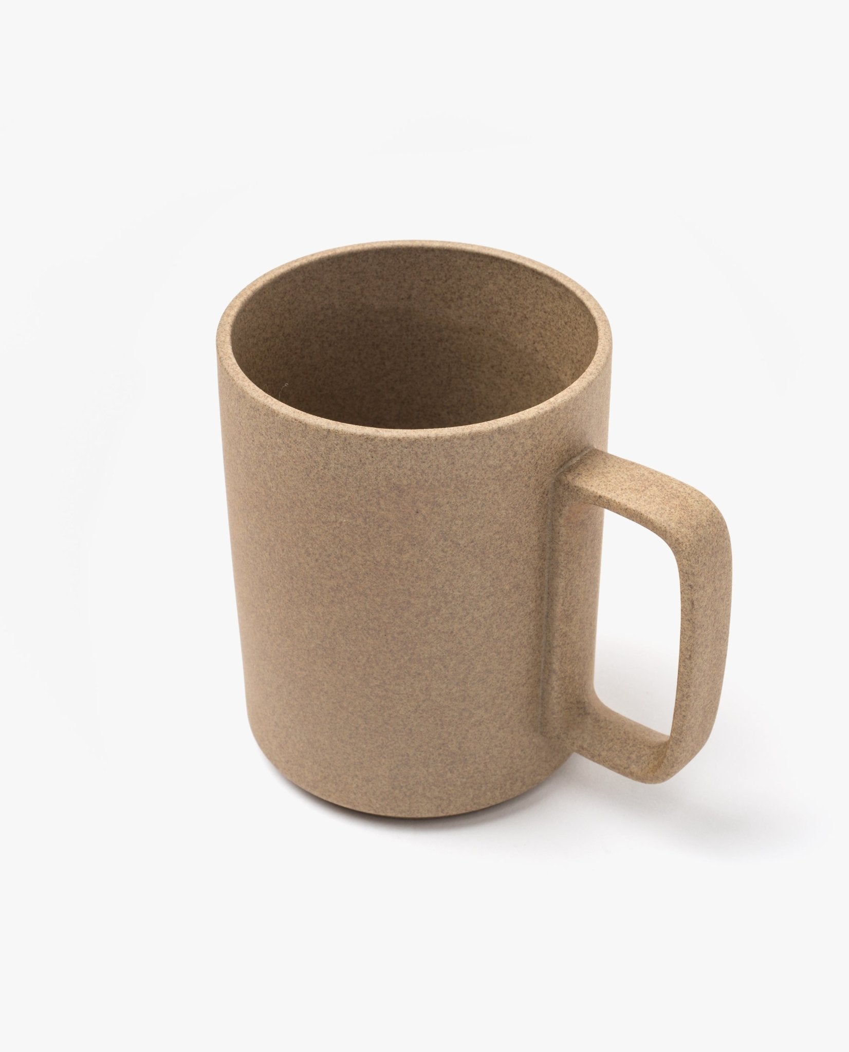 The Hasami Porcelain Mug (Natural) features a plain, light brown finish with a smooth texture and a squared handle, set against a white background. Inspired by Japanese ceramics, this handmade mug embodies minimalist elegance and timeless design.