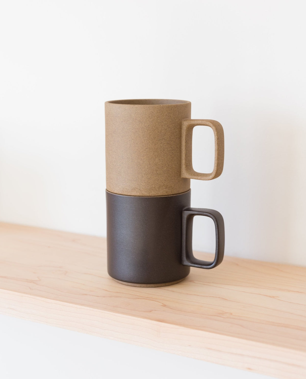 A Hasami Porcelain Mug (Matte Black) sits atop a light wooden shelf against a plain white background, highlighting the timeless elegance of Japanese craftsmanship.