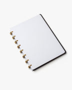 The Discbound Heirloom Journal (Black Leather - Standard 6" x 8.5") features refillable dotted white pages and gold rings, displayed open on a white background.