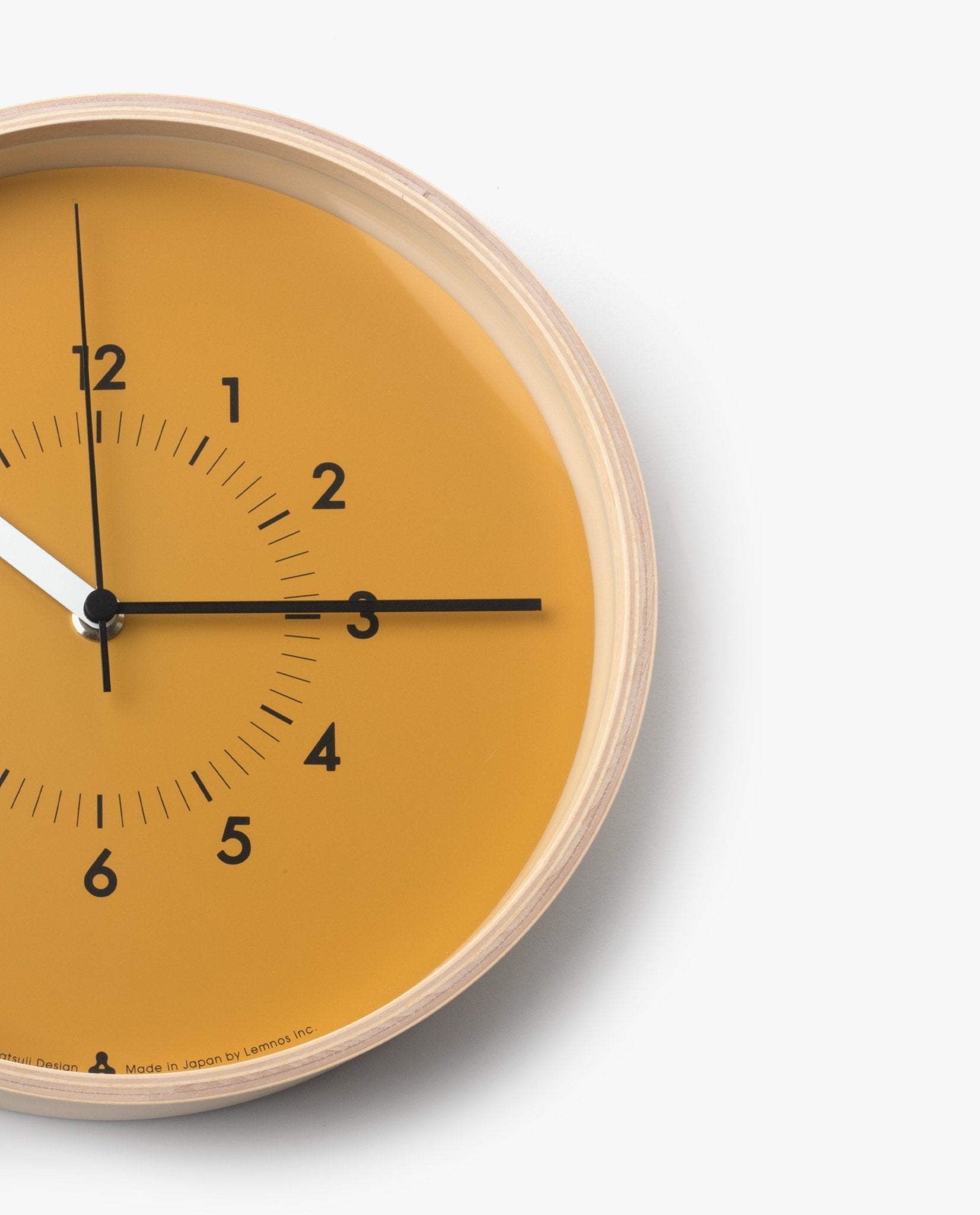 The Lemnos SOSO Clock (Orange) is a round plywood wall clock with an orange face and minimalist black numbers. The time shows 12:15:15. This minimalist clock features black hour and minute hands, a white silent sweeping second hand, a light wood edge, and is set against a white background.