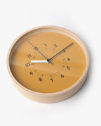 The Lemnos SOSO Clock (Orange) is a round minimalist wall clock featuring an orange face, black numbers, black hour and minute hands, and a white second hand with silent sweeping movement, all encased in a light plywood frame.
