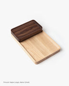 A beautifully handcrafted Valet Tray (Maple - Large) featuring smooth, rounded edges is paired with a smaller, darker walnut tray stacked in one corner, both elegantly displayed against a white background.