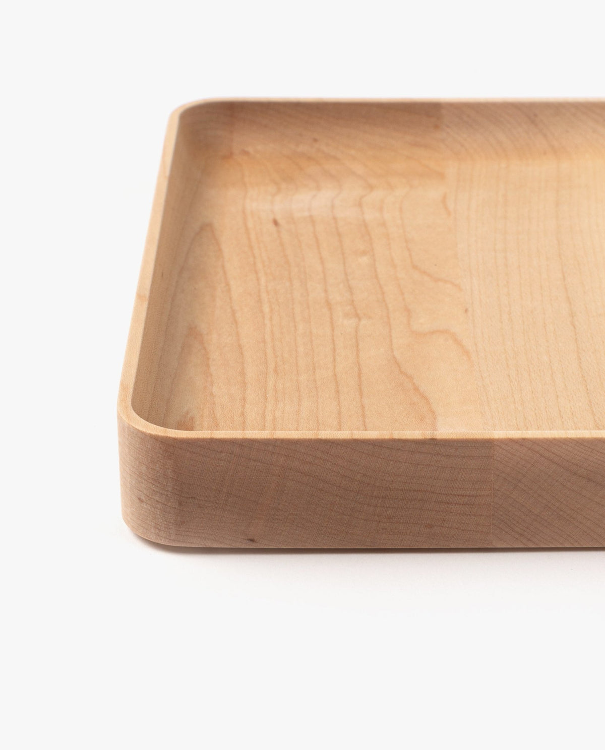 A close-up of the Valet Tray (Maple - Medium) with rounded corners and smooth finish, partially shown against a white background to emphasize its shallow depth and natural maple wood grain.