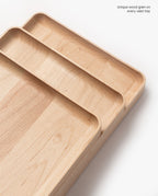 A handcrafted rectangular Valet Tray (Maple - Medium) sits on a white background, displaying unique natural wood grain. Text in the top right corner reads, Unique wood grain on every valet tray.