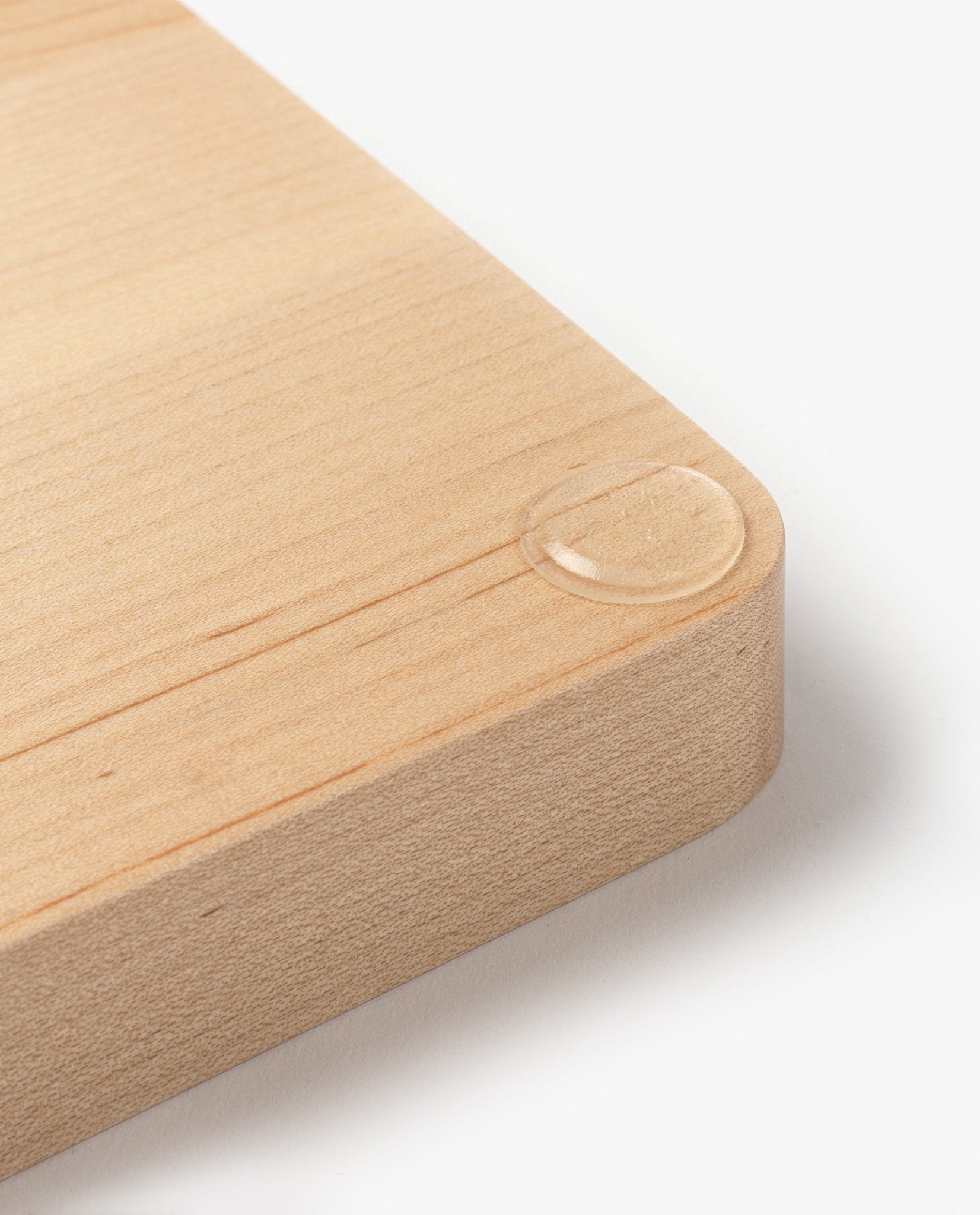 A close-up of the Valet Tray (Maple - Medium) corner shows a single water droplet resting on its smooth, handcrafted maple surface. Set against a plain white background, it highlights the tray's quality as a decorative or organizational accent.