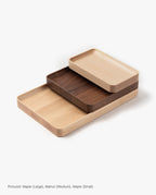 Three handcrafted "Valet Tray (Maple - Small)" trays—each in a different size and wood finish, including light maple, medium walnut, and solid maple—are stacked on top of each other against a white background. Every valet tray showcases the natural beauty and expert quality of fine woodwork.