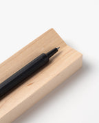 A black pen rests on the Pen Tray (Maple), a rectangular, light-colored pen holder made in Pennsylvania, set against a white background.