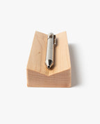 A silver metal pen rests horizontally on the Pen Tray (Maple), a rectangular solid maple block with a groove, shown from the tip-end on a plain white background. This elegant piece is expertly made in Pennsylvania.