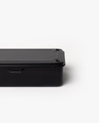 Partially shown against a plain white background, the Toyo Steel Stackable Storage Box T-190 (Black) features a black rectangular metal design with rounded edges and visible screws on the lid, highlighting its classic stackable toolbox style.
