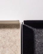 Close-up of two adjacent rectangular trays, featuring the Gather Note Tray (1x1 - Black) with a dark gray felt interior, alongside a white tray with a beige felt interior—both thoughtfully Made in the USA and separated by a narrow gap.