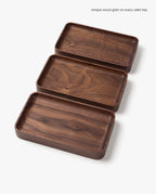 Three handcrafted Valet Tray (Walnut - Small) pieces, made in Pennsylvania with unique wood grain patterns, are displayed in a staggered arrangement on a white background. Caption: Unique wood grain on every valet tray.