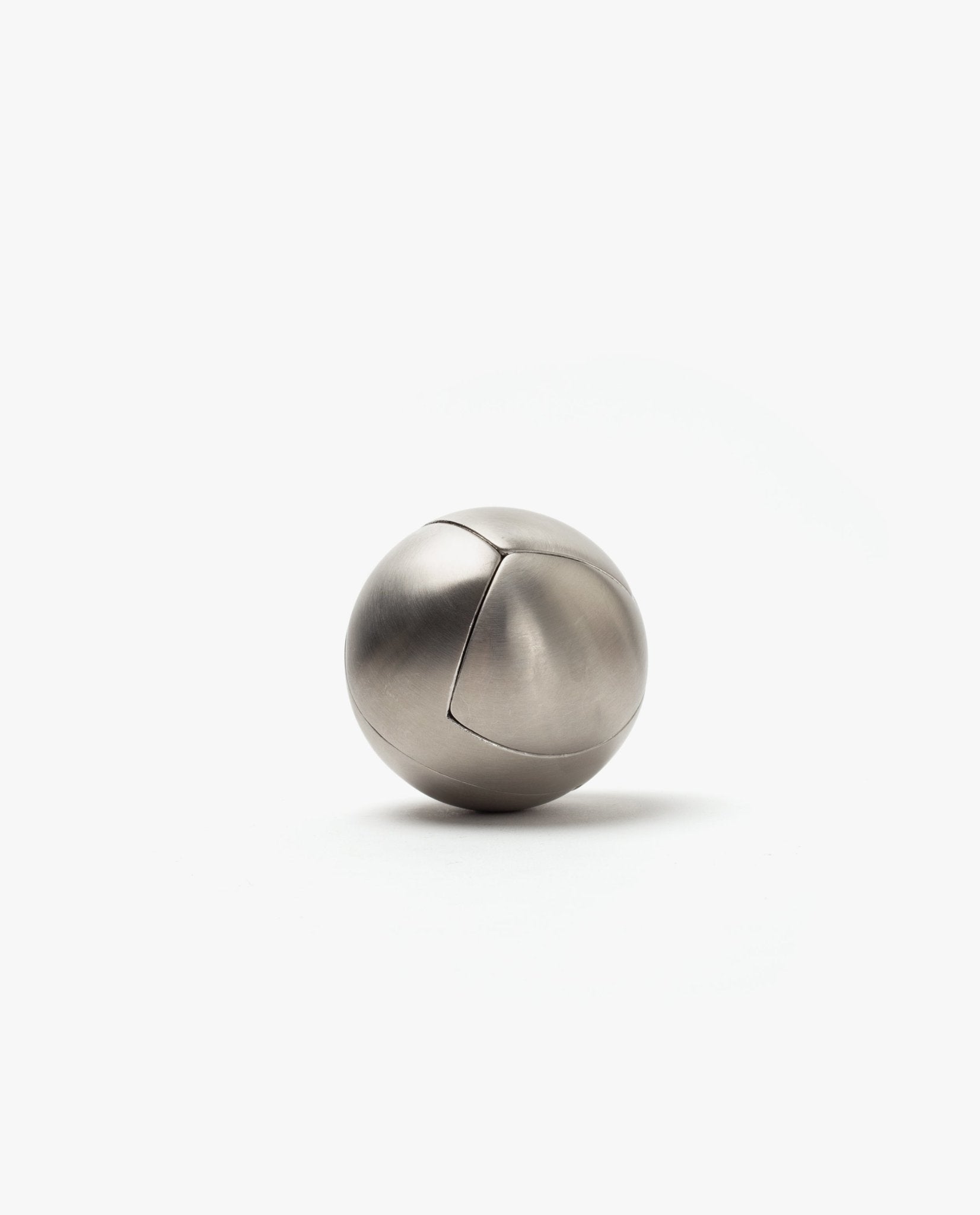 The Craighill Venn Puzzle (Stainless Steel) is a smooth, metallic sphere with a subtle curved seam, elegantly resting on a plain white background.